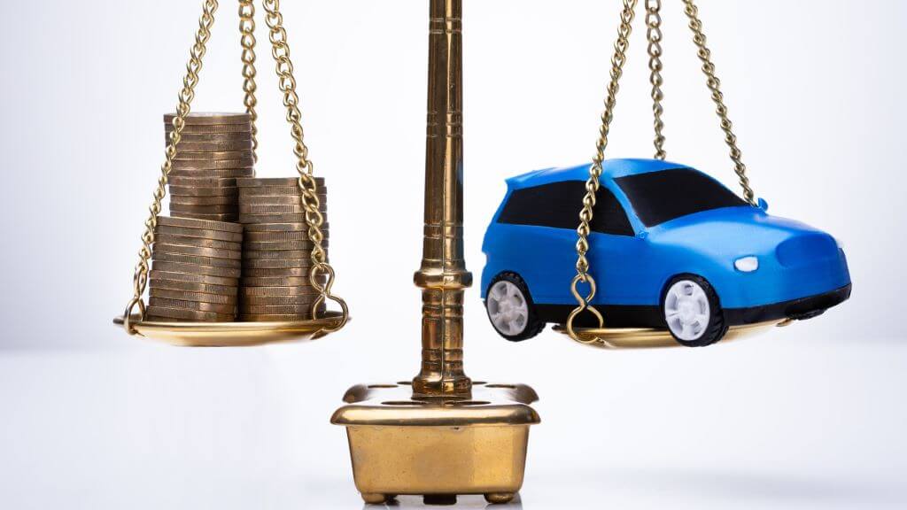 A scale balancing a car and coins.