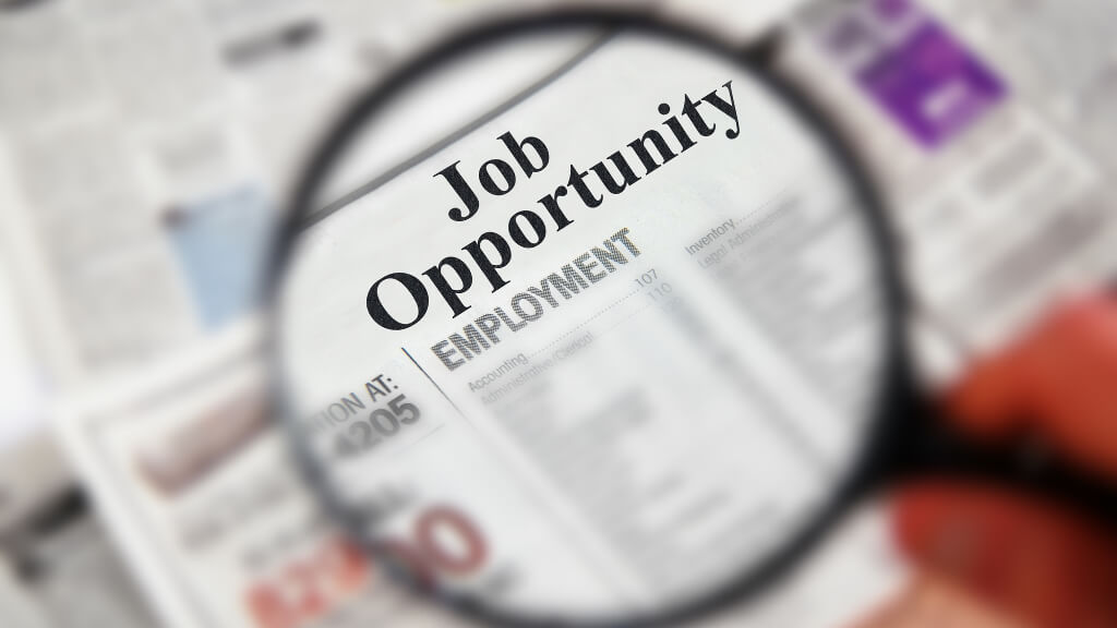 Job Opportunity section of a newspaper highlighted under a magnifying glass.